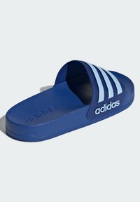 Chinelo azul da Adidas com uma sola de borracha texturizada, abertura na frente, e três riscas azul-claro na parte superior. Apresenta uma marcação em relevo na lateral.