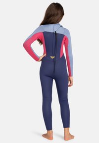 Volledige wetsuit in navy, roze en lichtblauw. Lange mouwen, getailleerd ontwerp, soepele textuur. Rugrits met logo-accent nabij de taille.