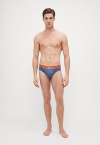 Boxeri pentru bărbați, de culoare albastră, cu un elastic de culoare maronie în contrast, inscripționat cu un logo. Materialul pare neted, având un design ajustat și cusături minime.