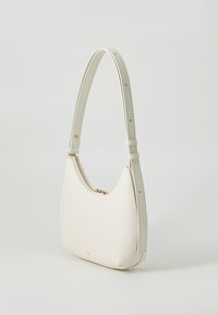 Bolsa de mão de couro branco com formato curvado, apresentando um fecho de zíper e alça ajustável. Textura suave e branding discreto na base.