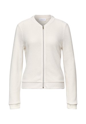 Veste blanche texturée à manches longues avec fermeture éclair devant, poignets côtelés et col arrondi, présentée sur un fond uni.