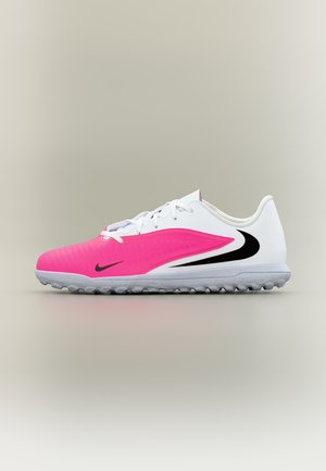 Chaussure de sport basse avec une tige blanche, un panneau latéral rose vif, un logo Nike noir, des lacets blancs et une semelle texturée grise conçue pour les surfaces en gazon artificiel.