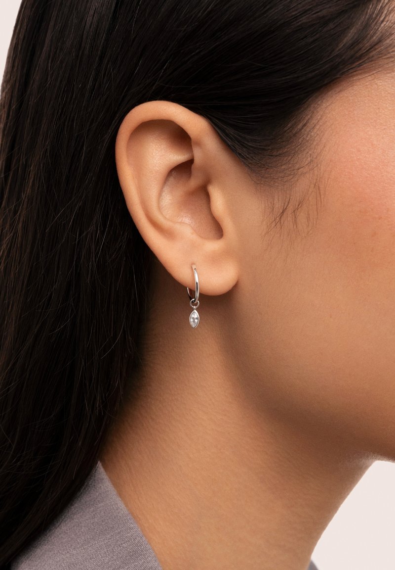 Orecchino a cerchio in argento con un piccolo pendente in pietra marquise. Texture liscia, design semplice e stile minimalista.