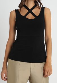 Top senza maniche nero con scollo a V e spalline incrociate. Realizzato in materiale morbido con un design aderente.