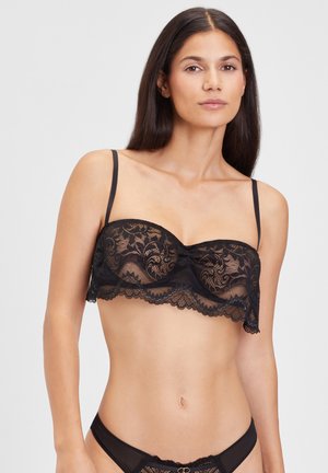 Zwarte kant bralette met een geschulpte rand, verstelbare bandjes en ingewikkelde bloempatronen door de stof heen.