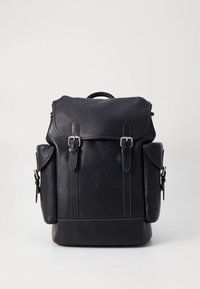 Svart läderryggsäck med en strukturerad design, utrustad med justerbara remmar, lockstängning och sidofickor. Silverfärgade metallaccenter.