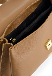 Tan leather handbag with a textured finish. Features a gold zipper and metal accents. The interior is black with zippered compartment.