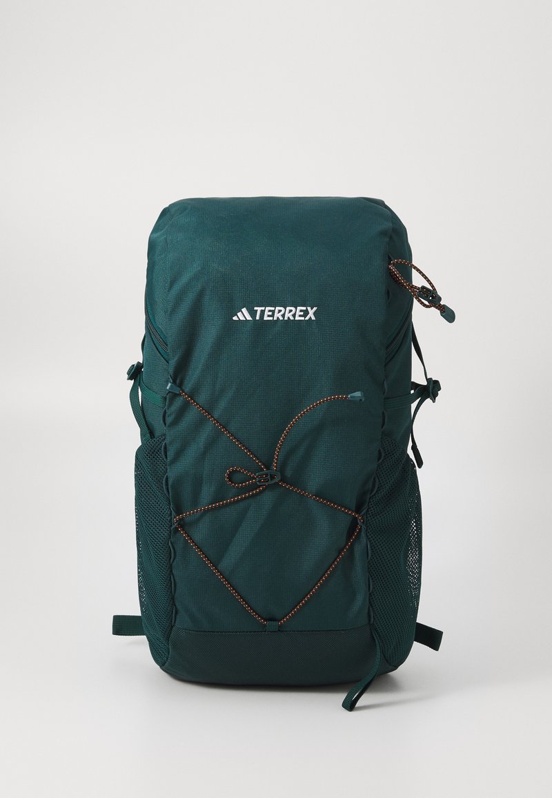 Tamnozeleni ruksak s teksturiranim materijalom, s prilagodljivim sustavom užadi, mrežastim bočnim džepovima i bijelim "TERREX" logotipom na prednjoj strani.