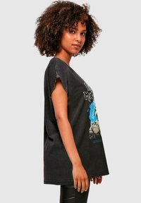 Sort oversized T-shirt lavet af bomuld; har et grafisk design med farverne blå og grå. Rå kant på ærmerne, let slidt finish.