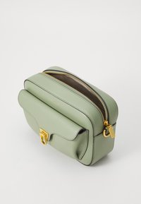 Green leather crossbody bag with dual zippers, gold hardware, a front flap pocket, and a textured finish. Features a contrasting brown interior.