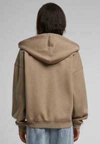 Kreemikas kapuutsiga suuruse järgi oversized sviiter, millel on suur kapuuts, langenud õlavarred, soonikkoes mansetid ja äär. Sile tekstuur, lõdva siluett.