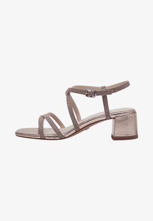 Strappy sandal in metallic rose gold, featuring shiny leather upper, block heel, and adjustable ankle strap with a buckle.