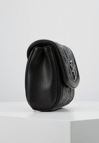 Black leather bag with quilted texture, rounded shape, and a flap closure featuring a metallic accent. Smooth finish and compact design.