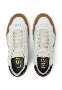 Un paio di sneaker bianche con punte in suede marrone, lacci beige e sole interne nere etichettati "SINISTRO" e "DESTRO" in testo dorato.