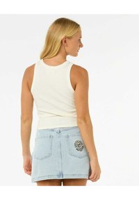 Hvid ribbet tanktop med rund hals, parret med en lyseblå denimnederdel med broderede detaljer på baglommen.