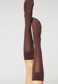 Brune knæhøje strømper lavet af gennemsigtigt materiale med en solid, ribbet kant. Designet har en glat tekstur og en tætsiddende form.