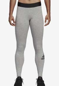 Harmaat treenilegginsit mustalla vyötäröllä, valmistettu pehmeästä ja joustavasta kankaasta. Alhaalla vasemmassa sääressä on musta logo.