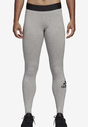 Grijze workout leggings met een zwarte tailleband, gemaakt van een zachte, elastische stof. Bevat een zwart logo accent op de onderkant van het linkerpijpje.
