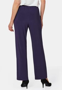 Paarse wijde broek met elastische tailleband, gladde textuur en afgewerkte randen, gecombineerd met zwarte hoge hakken.