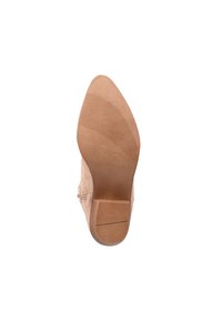 Suela de zapato de tacón alto nude con textura suave, punta redonda y líneas de agarre de goma. Presenta un diseño de tacón bloque modesto.