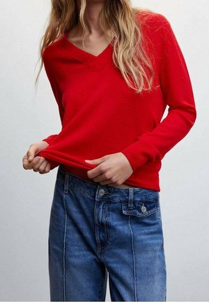 Rode V-hals trui van glad breimateriaal, gecombineerd met high-waisted blauwe denim jeans, met een relaxte pasvorm en klassieke styling.