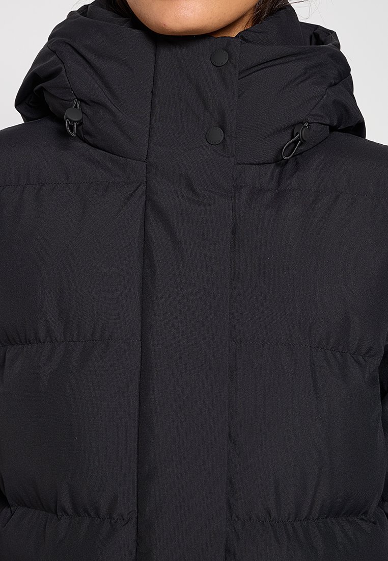 Schwarze Steppjacke mit hohem Kragen, ausgestattet mit doppeltem Druckknopfverschluss und verstellbarer Kapuze. Glatte Textur und gesteppte Optik.