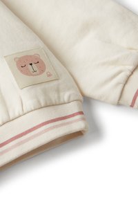 Felpa per bambino color crema con maniche e polsini a costine, caratterizzata da strisce rosa e da un patch raffigurante la faccia di un orsetto che dorme.