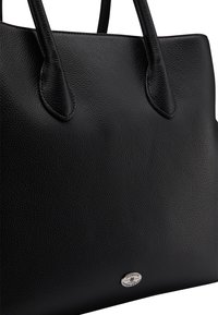 Sac fourre-tout en cuir noir avec surface texturée, deux poignées robustes et un accent en logo argenté en bas. Design simple et structuré.