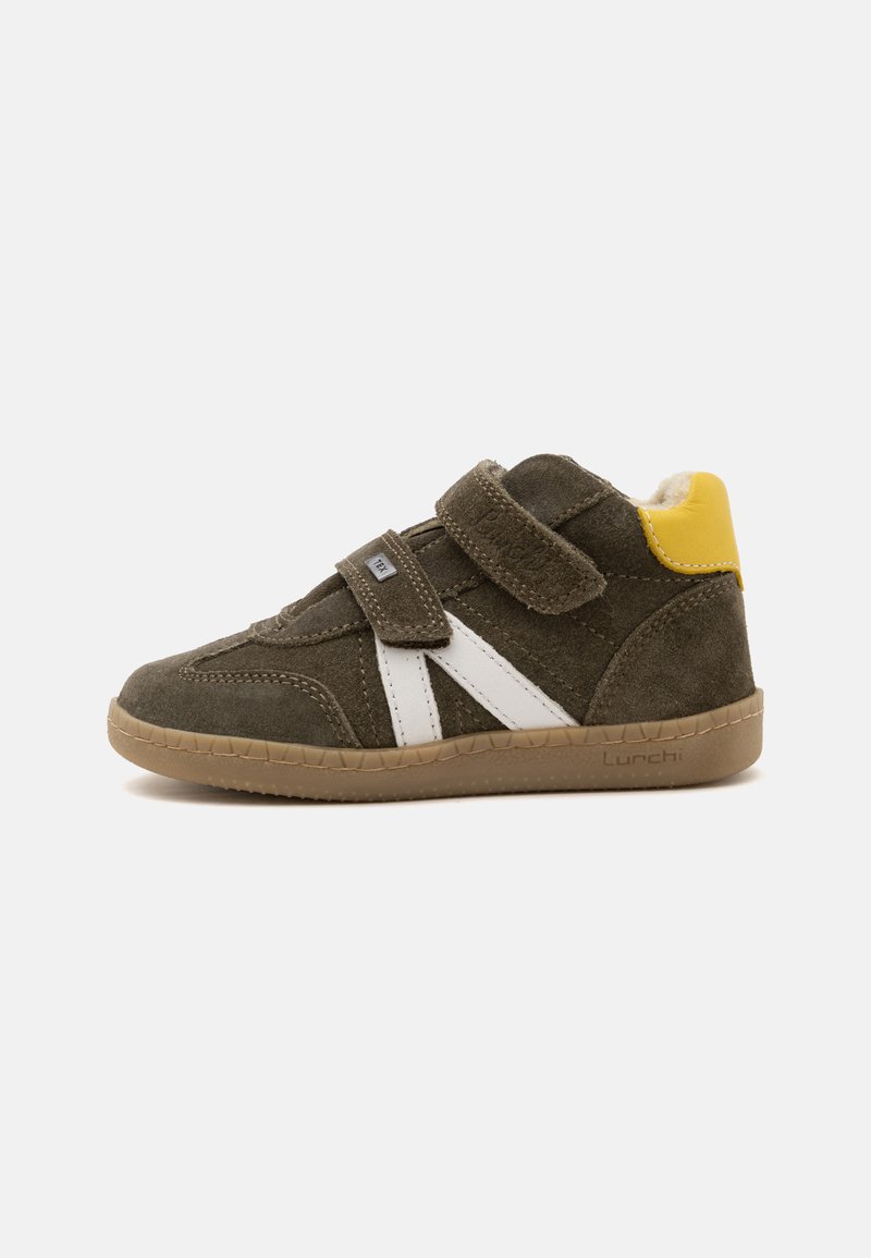 Baskets en daim marron pour enfants avec deux bandes Velcro, bandes blanches latérales, détail jaune au talon et semelle en caoutchouc sur fond uni.