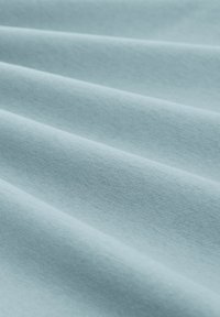 Tessuto azzurro chiaro con una superficie liscia, che mostra lievi ondulazioni e pieghe, realizzato in materiale morbido. Nessun motivo o dettaglio visibile.