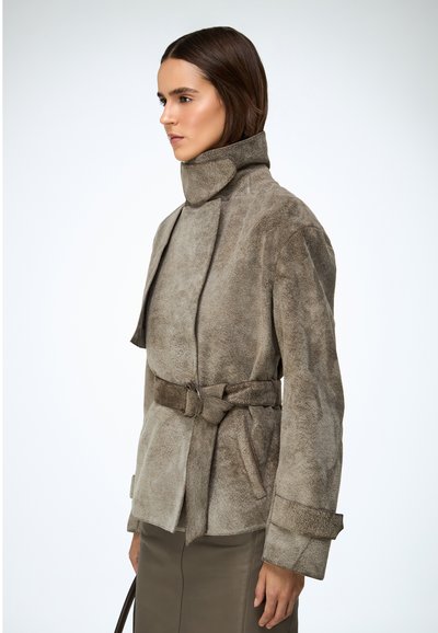 Világosbarna velúr dzseki magas gallérral, öves derékkal és bővülő ujjakkal. Sima textúrájú és minimalista kialakítású.