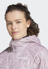 Svetle fialová bunda Terrex s prošívanou texturou a kapucí. Má přední zip a detail loga na horní části hrudi.