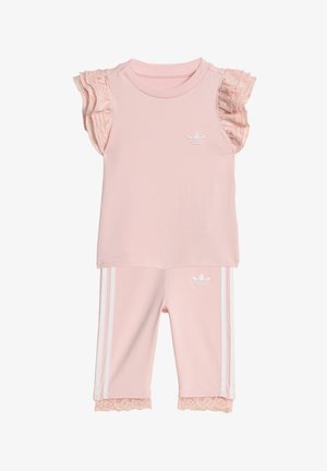 Kleinkind-Rosa Adidas-Outfit mit gerafften Spitzenärmeln, Spitzenbesatz an der Hose, weißem Logo auf Brust und Hose sowie weißen Seitenstreifen an der Hose.