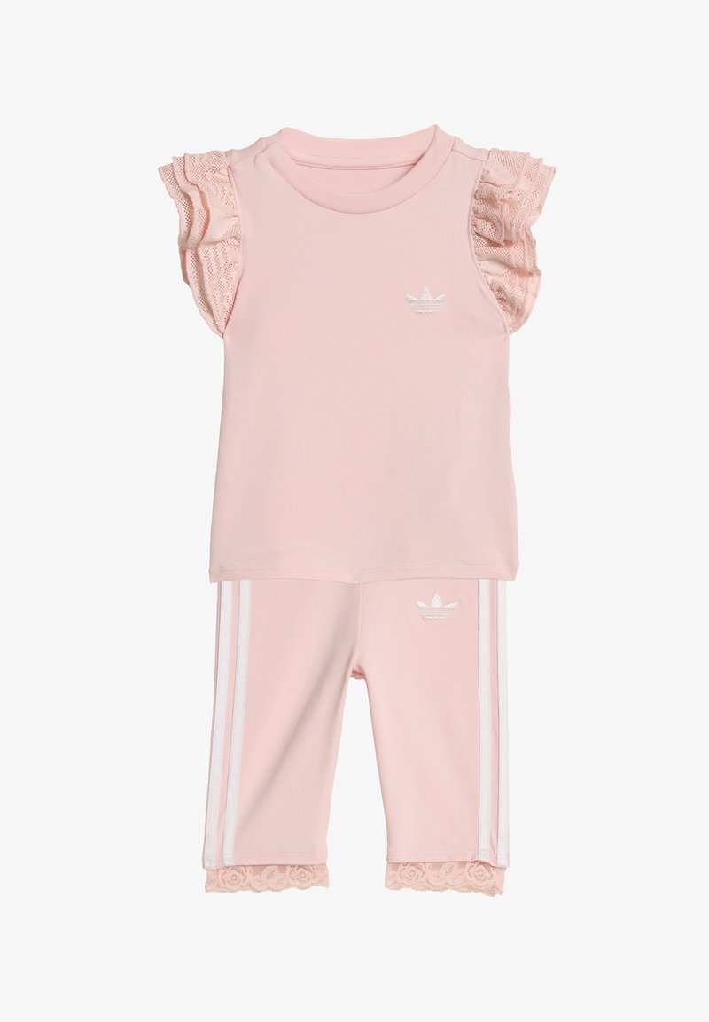 Kleinkind-Rosa Adidas-Outfit mit gerafften Spitzenärmeln, Spitzenbesatz an der Hose, weißem Logo auf Brust und Hose sowie weißen Seitenstreifen an der Hose.