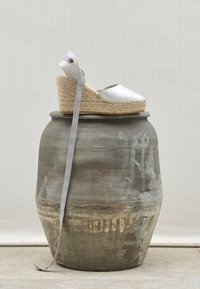 Sølv satin espadrille kilehæl med en indpakket anklerem, jutesål og tekstureret stof, vist på en grå keramisk vase.