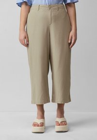 Beige wijde broek met een gladde textuur, voorzien van een knoopsluiting aan de voorkant en stiknaden aan de onderkant, gecombineerd met platform sandalen.