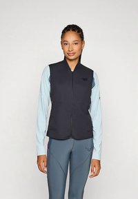 Musta hihaton liivi, jossa vetoketjusuljenta edessä, yhdistetty vaaleansiniseen pitkähihnaiseen paitaan. Liivissä on hillitty rintalogo.