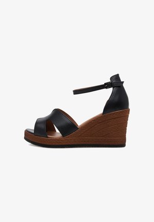 Sandalias cuña de cuero negro con punta abierta, con un diseño entrecruzado en la parte delantera y un tacón cuña marrón texturizado. Correa ajustable en el tobillo.