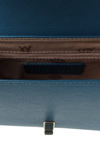 Portafoglio strutturato color teal con scomparto con zip, fodera interna marrone e chiusura a fermaglio in metallo. L'etichetta "Steve Madden" è visibile all'interno.