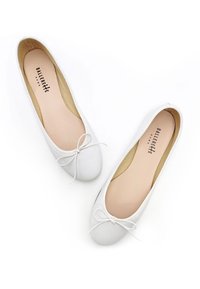 Ballerines blanches en cuir lisse, avec un bout arrondi, une fine bordure blanche et un nœud décoratif à l'avant.