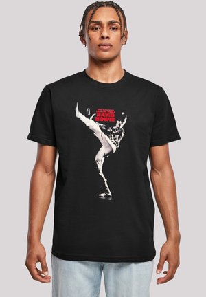 Black cotton t-shirt featuring a graphic print of a dancer in black and white. Text reads "THE MAN WHO SOLD THE WORLD DAVID BOWIE" in red.