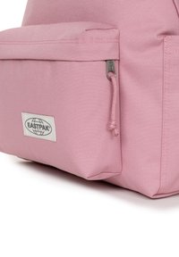 Mochila Eastpak rosa con un tejido texturizado, bolsillo frontal con cremallera y un parche de logo en la sección frontal inferior.