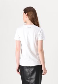 White cotton t-shirt with short sleeves and a crew neckline, featuring a black "KARL LAGERFELD" logo on the upper back.