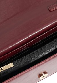 Bordeaux leren handtas met een glanzende afwerking, voorzien van een ritssluiting zwart binnenvak en gouden hardware op de flapsluiting.