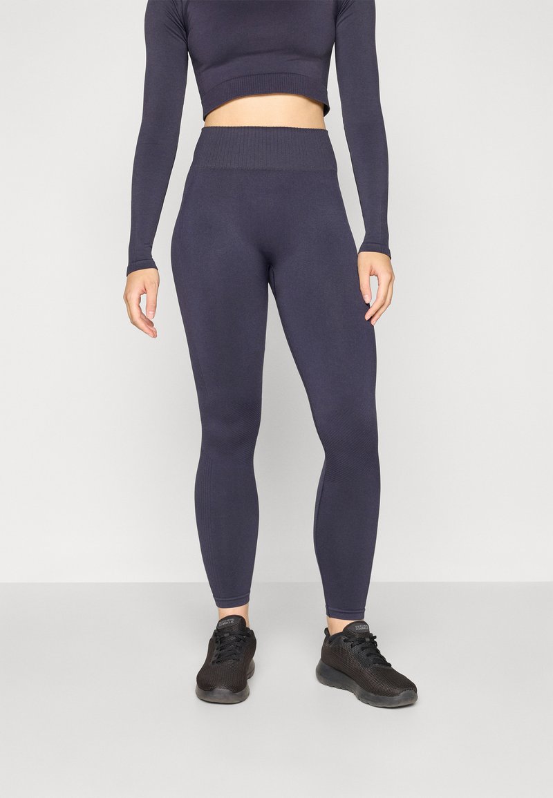 Dark navy fitted leggings with a high waistband and ribbed texture, paired with a matching long-sleeve crop top. Black athletic shoes.