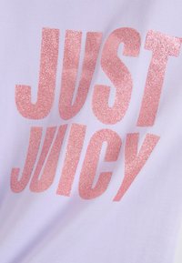 Valge T-särk, millel on suur, sädelev roosa tekst "JUST JUICY." Pehme kangas, vabaaja disain ja ümar kaelus.