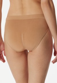 Hellbraune nahtlose Unterwäsche mit dehnbarem Bund, glatter Textur und minimalen Ziernähten, entworfen für Komfort und Passform.