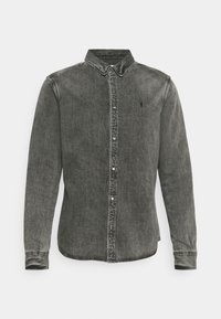 Grå denimskjorta med knappstängning fram, spetsig krage, långa ärmar och en subtil logotyp på bröstet. Har en urtvättad textur.