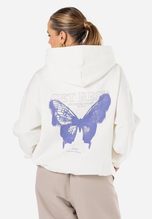 Biała, oversize'owa bluza z kapturem z fioletowym grafiką motyla na plecach oraz napisem "ODPOCZYWAJ. ALE NIGDY NIE ZAPOMINAJ LATAĆ."