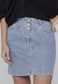 Vaaleansininen farkkuinen minihame, joka on muotoiltu tiukasti. Siinä on viisi nappia vyötäröllä, huomaamattomat taskut ja sileä pinta.